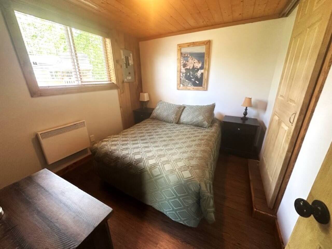 Une chambre à coucher avec un lit, des tables de chevet, une fenêtre et une porte.