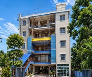 A multi-story hotel with a central atrium, balconies, and a blue and yellow facade. - Standard Room Pratikshya & Pratistha (Balianta)