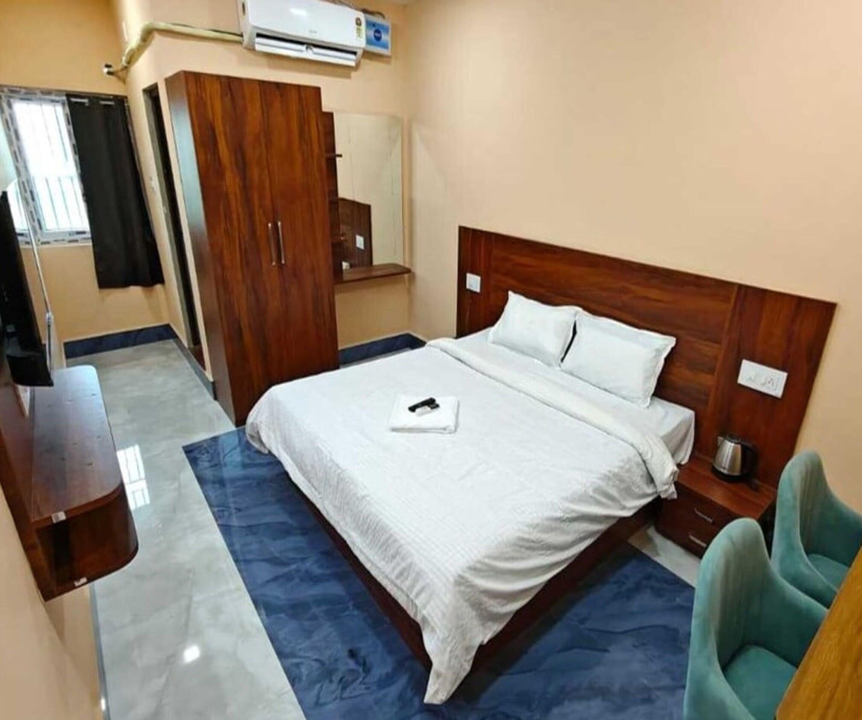 Een hotelkamer met een bed, een kledingkast, een nachtkastje, een stoel en een airconditioner.