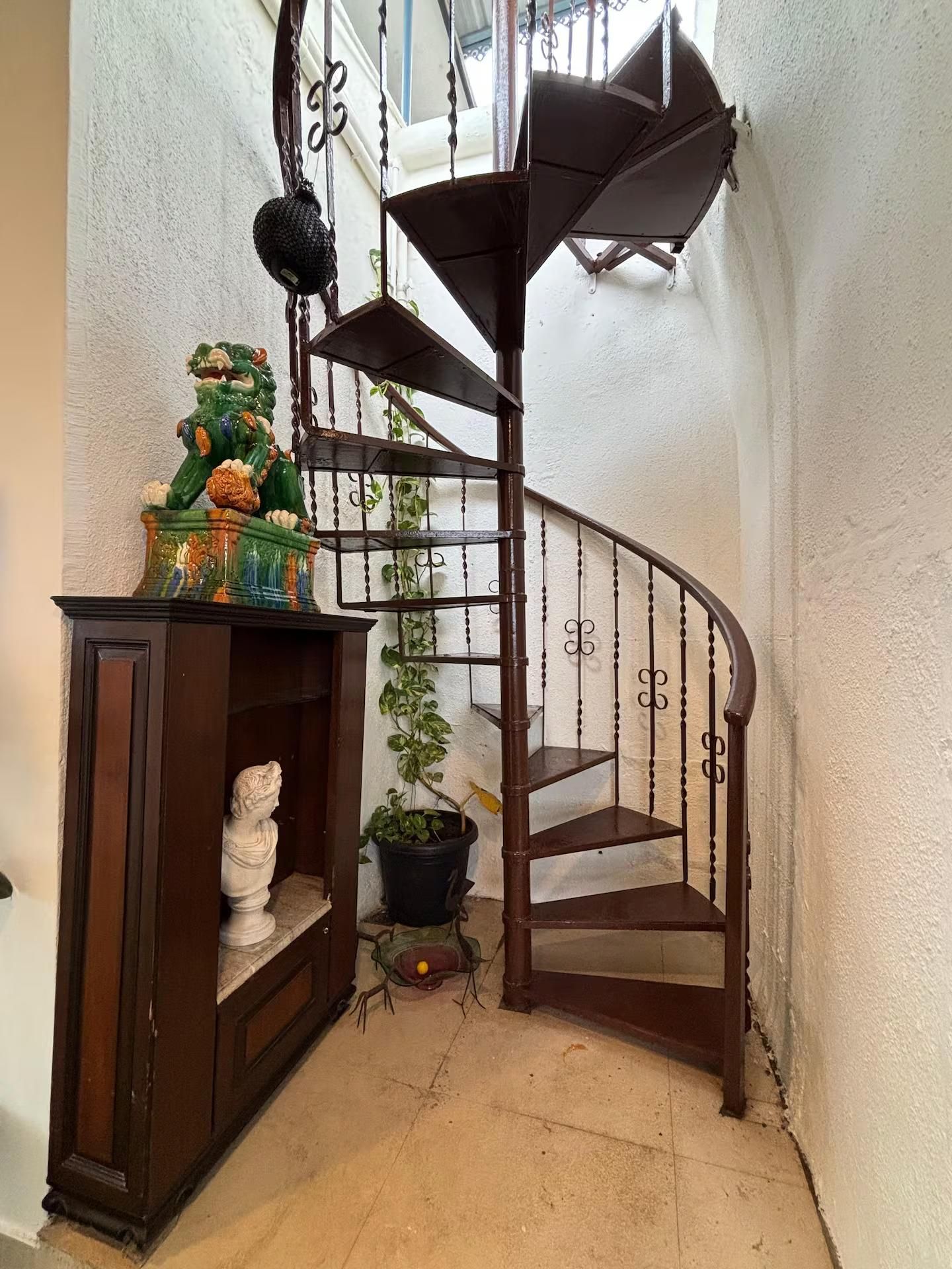 A spiral staircase with a wooden handrail and a black metal railing.