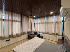 Een hotelkamer met een bed, een bureau, een stoel en een plafondventilator.