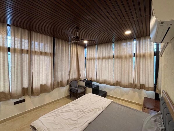 A hotel room with a bed, a desk, a chair, and a ceiling fan.