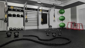 Una palestra con cinghie di sospensione TRX, kettlebell, palle mediche e una piattaforma rialzata rossa.