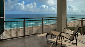 Un balcone con vista sull'oceano, una sedia e un pavimento piastrellato.