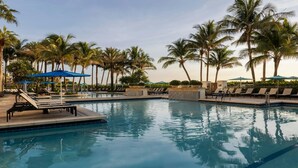 A pool area with lounge chairs and umbrellas, surrounded by palm trees. - Oceanfront Elegance Awaits – Discover Family Fun at Marriott’s Oceana Palms! (Riviera Beach)