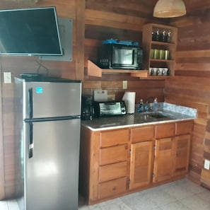 Une cuisine équipée d’un réfrigérateur, d’un four à micro-ondes, d’un grille-pain et de meubles de rangement en bois.