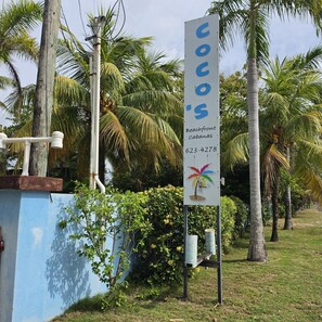 A sign for Coco's Beachfront Cabanas with contact information. - Placencia Belize TWO cabanas on the sea with a pool! (Placencia)