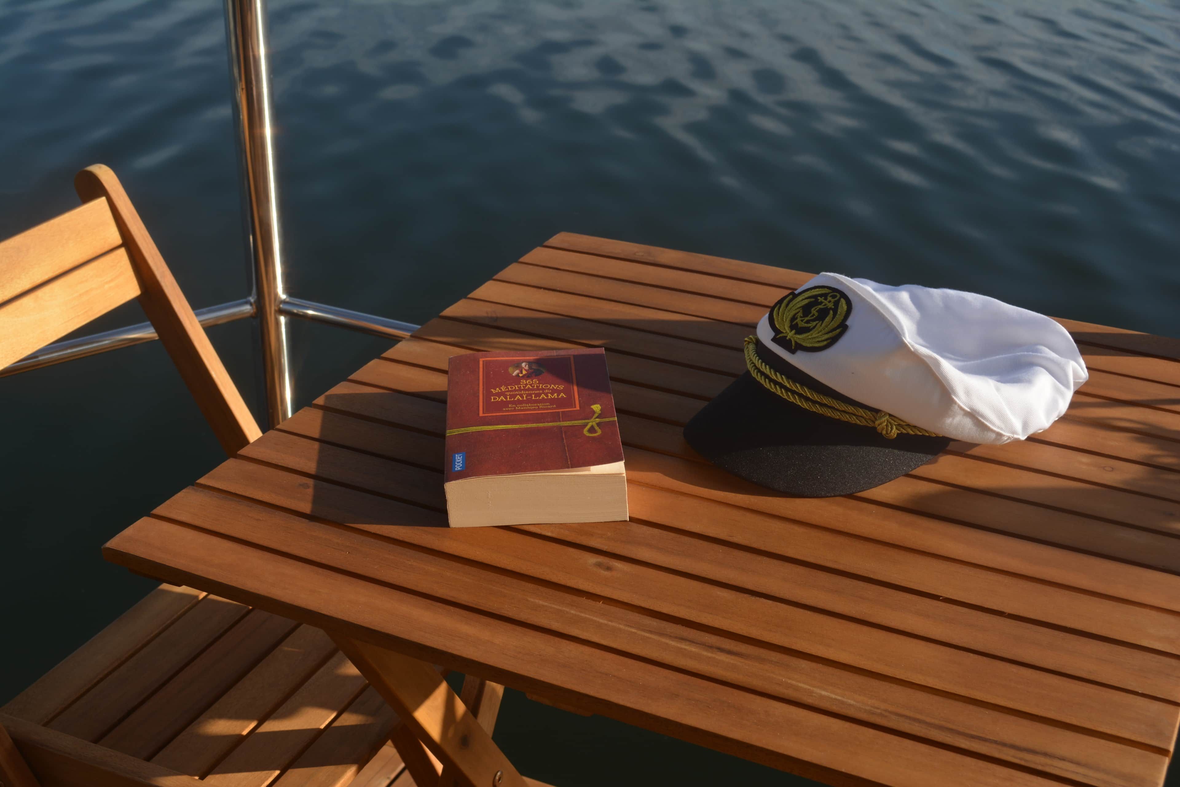 Ein Holztisch mit einem Buch und einer weißen Mütze darauf.