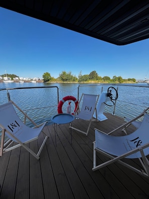 A deck with four lounge chairs, a small table, and a life ring.