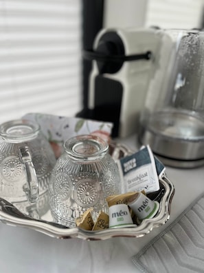 A tray with two glass pitchers, a coffee maker, and packets of coffee and tea.
