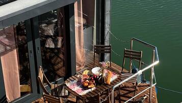 Un restaurante flotante con comedor, sillas, mesa dispuesta con comida y paneles solares en el techo.