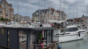 Un puerto deportivo con barcos amarrados, un edificio con balcón y una persona de pie en el muelle.