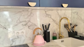 Een keuken met een marmeren aanrecht, een spoelbak, een waterkoker en een set messen.