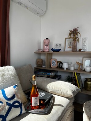 A cozy living room with a sofa, a bottle of wine, and a tray with a book and a remote control.