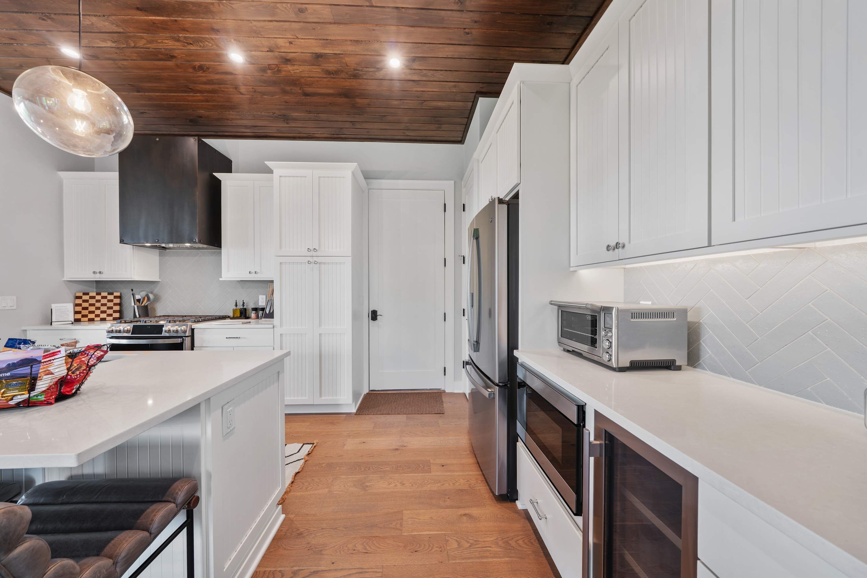 A modern kitchen with white cabinetry, a stainless steel refrigerator, a built-in oven, and a microwave.