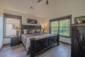 A bedroom with a large bed, two bedside tables, a headboard, and two windows. - Cove Reserve | Brand New | Sleeps 14 | Top 10% (Sevierville)