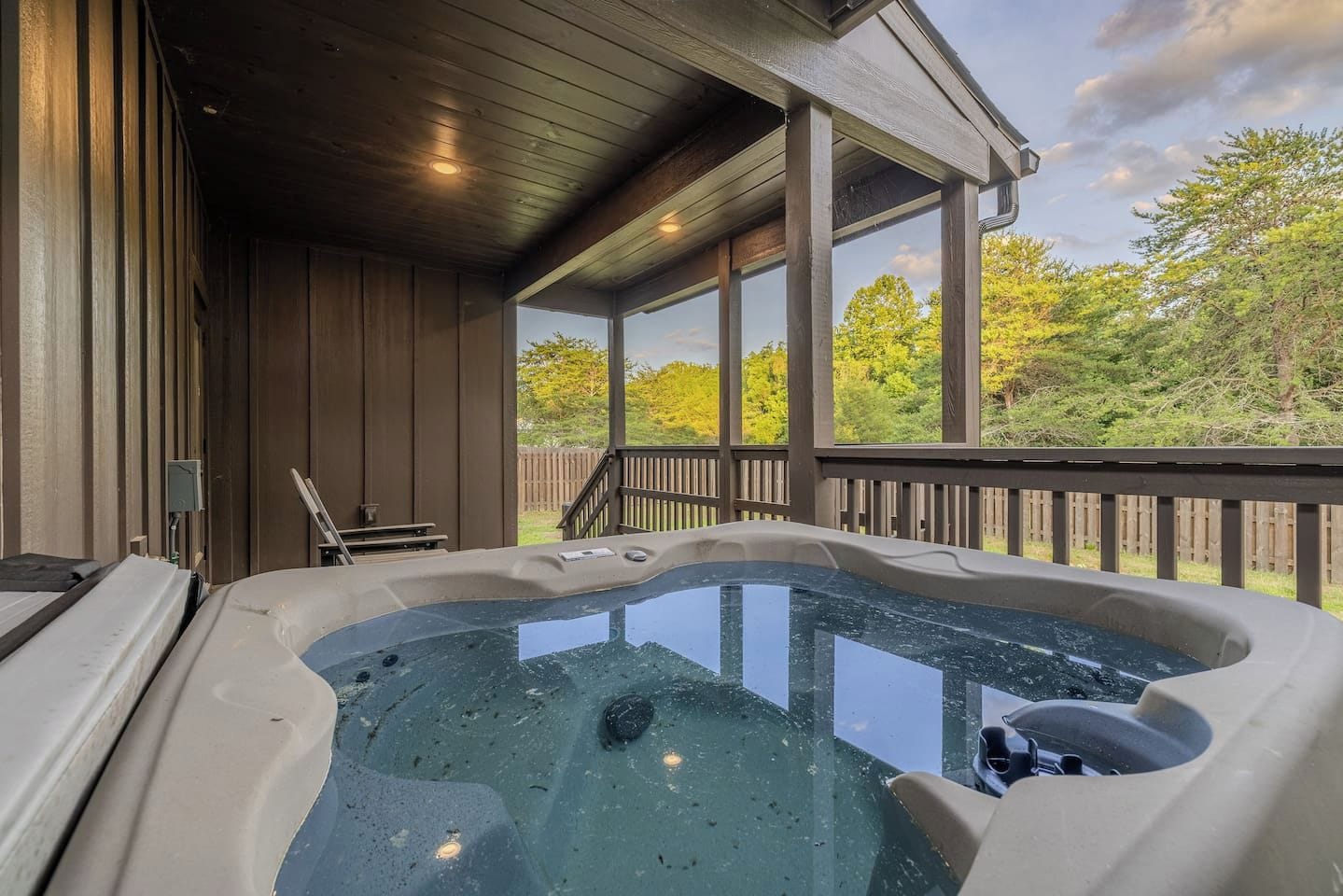 A hot tub on a wooden deck with a view of trees.
