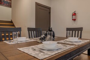 A dining table set with white plates, bowls, and cutlery, with a bear figurine centerpiece. - Cove Reserve | Brand New | Sleeps 14 | Top 10% (Sevierville)
