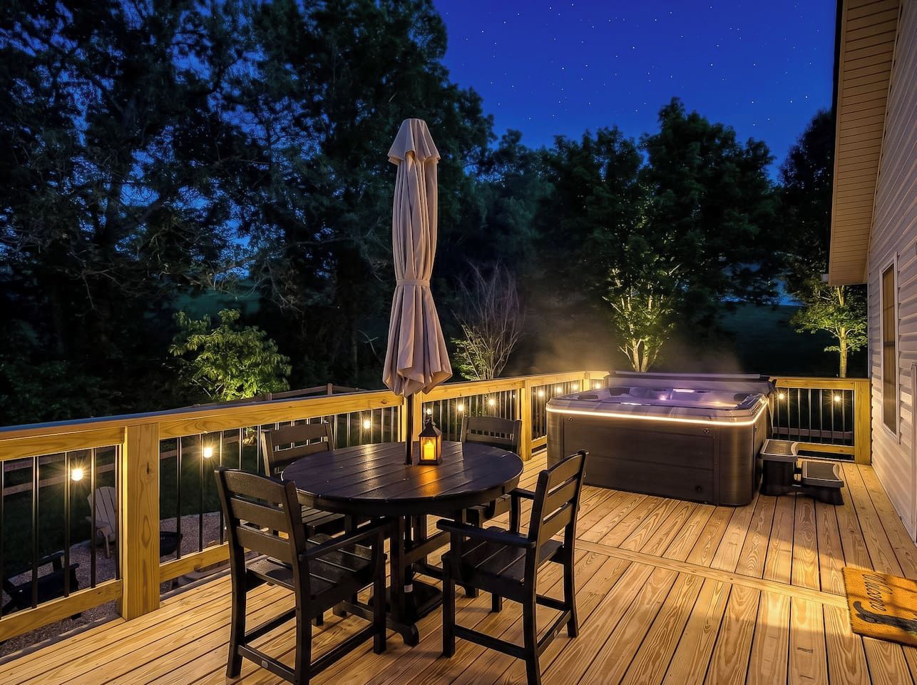 A wooden deck with a hot tub, a table with chairs, and a lantern.