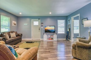 A living room with a brown leather sofa, a white entertainment unit, and a television. - Sleepy Cub Hollow! Dollywood | Fenced In | Hot Tub (Sevierville)