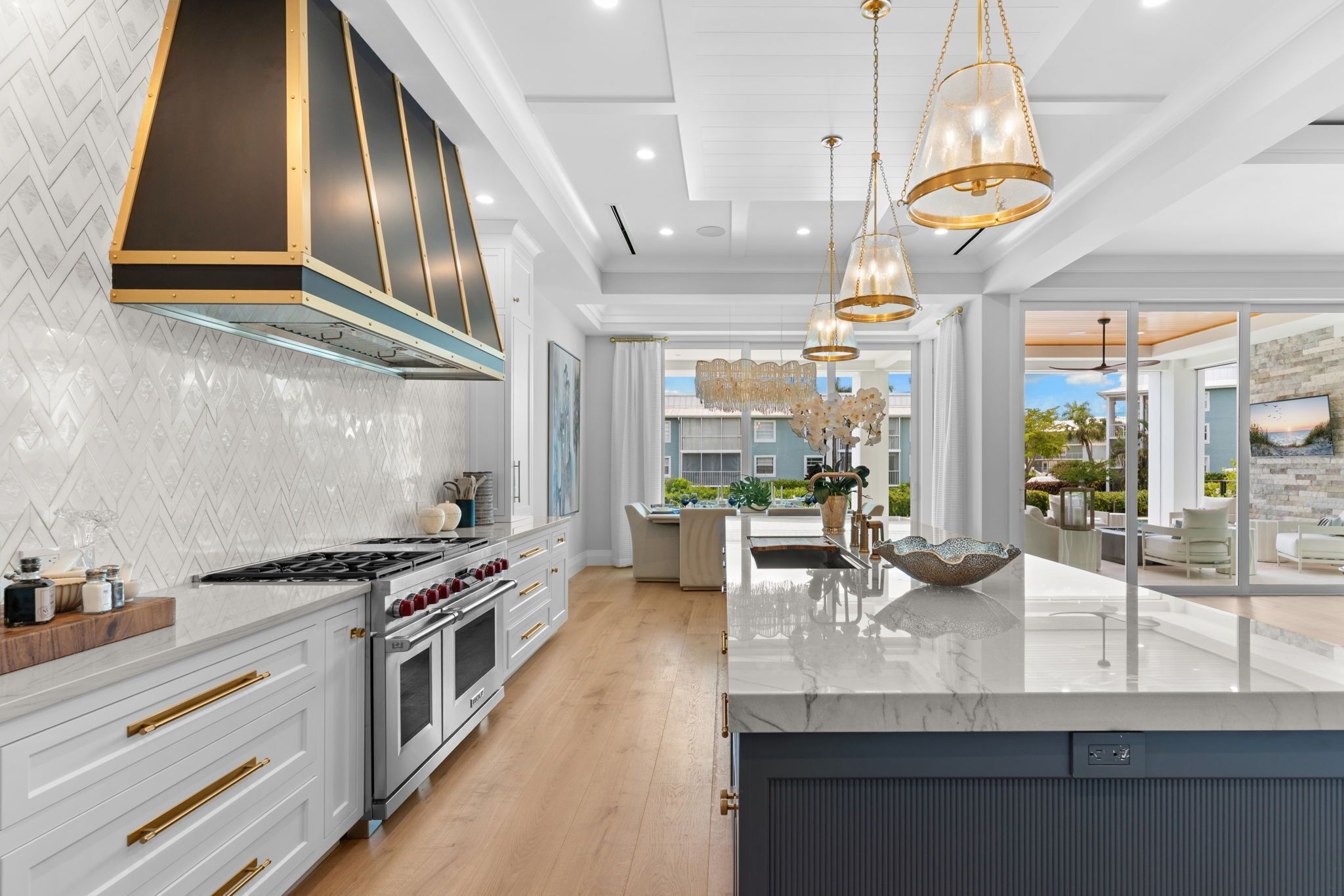 A modern kitchen with a large island, stainless steel appliances, and pendant lighting.