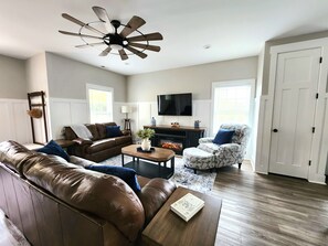 A living room with a brown leather sofa, a patterned armchair, a wooden coffee table, and a ceiling fan. - Woodland Retreat Minutes from Historic Bell Buckle Square (Bell Buckle)