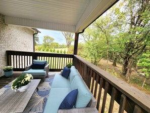 A covered outdoor seating area with a brick wall, wooden railing, and a view of a wooded landscape. - Woodland Retreat Minutes from Historic Bell Buckle Square (Bell Buckle)