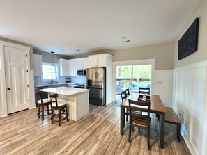A kitchen with white cabinets, a stainless steel refrigerator, and a wooden dining table with chairs. - Woodland Retreat Minutes from Historic Bell Buckle Square (Bell Buckle)