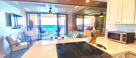 A modern kitchen with a central island, a microwave, and a dining area with a view of the ocean.