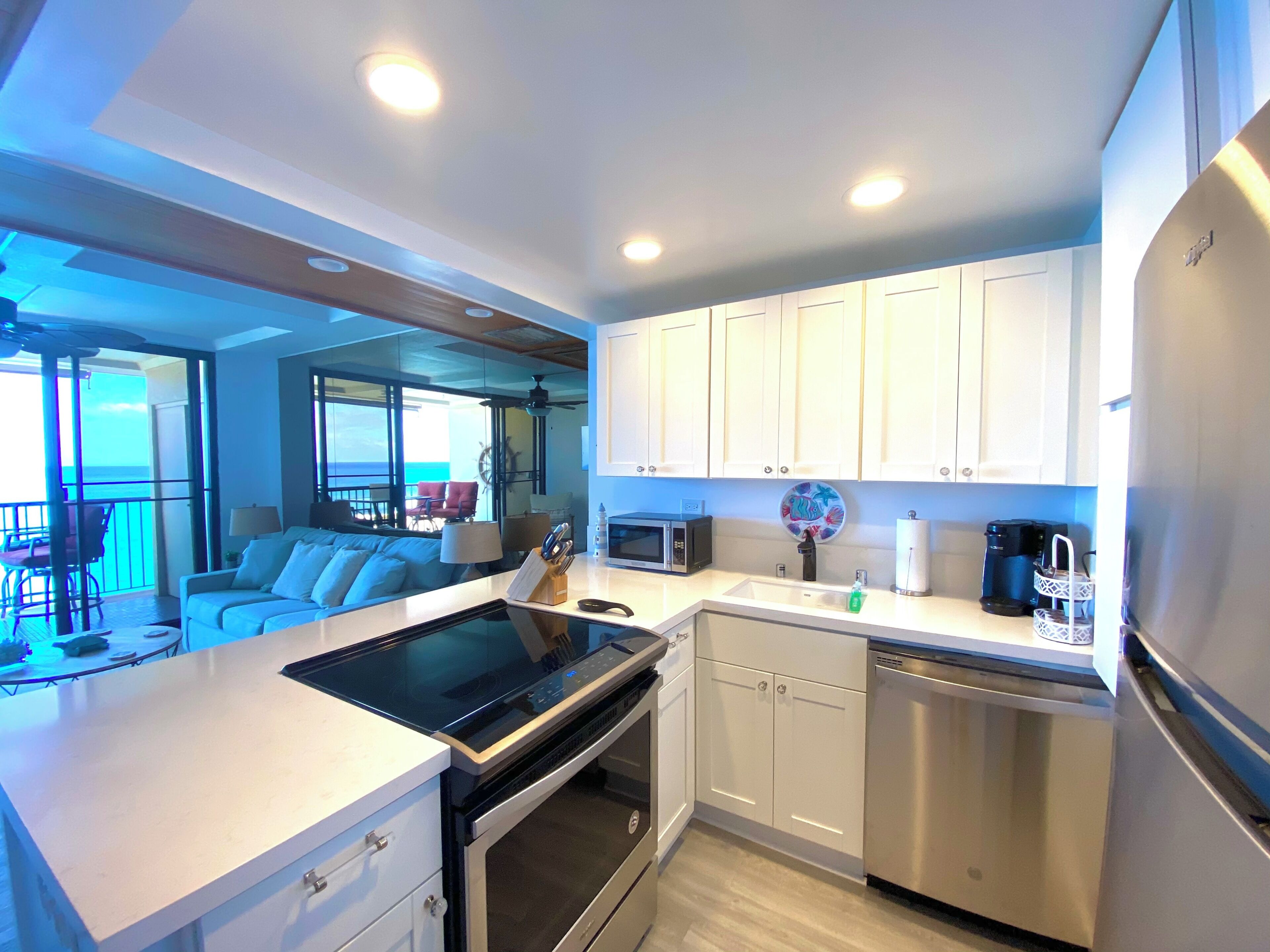 A modern kitchen with white cabinets, stainless steel appliances, and a view to the outside.