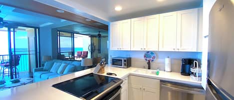 Una cocina moderna con armarios blancos, electrodomésticos de acero inoxidable y vistas al exterior.