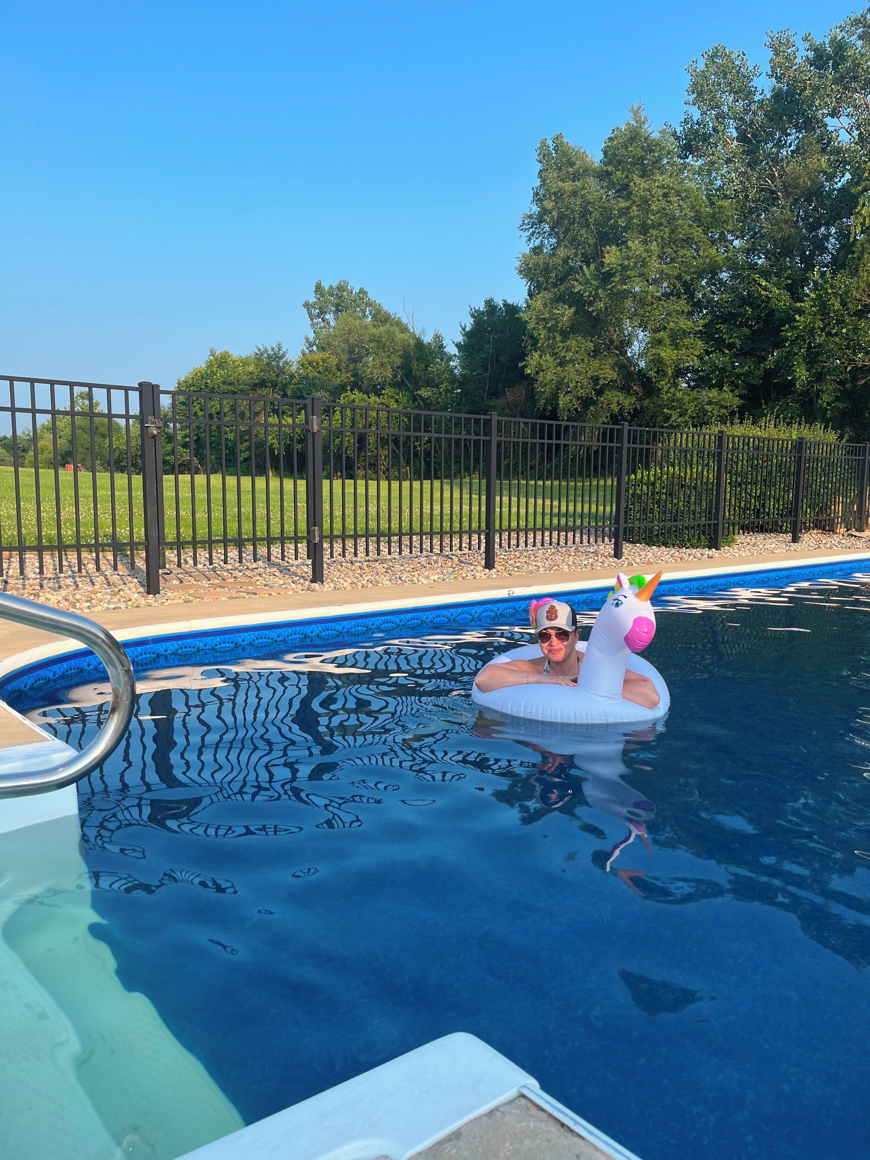 A swimming pool with a person in a unicorn float.