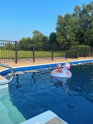 A swimming pool with a person in a unicorn float.