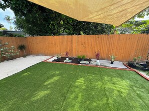 Un jardin avec une pelouse artificielle, une clôture en bois et diverses plantes en pot.