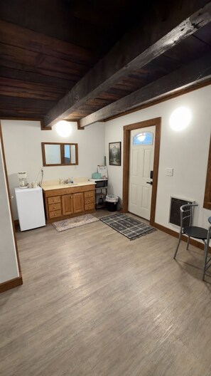 A compact kitchen with wooden cabinets, a refrigerator, a microwave, and a sink.