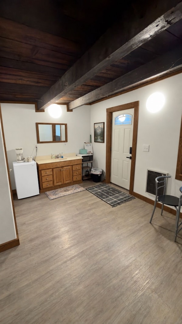 A compact kitchen with wooden cabinets, a refrigerator, a microwave, and a sink.