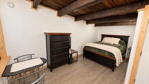 A bedroom with a bed, a dresser, a chair, and a small table.