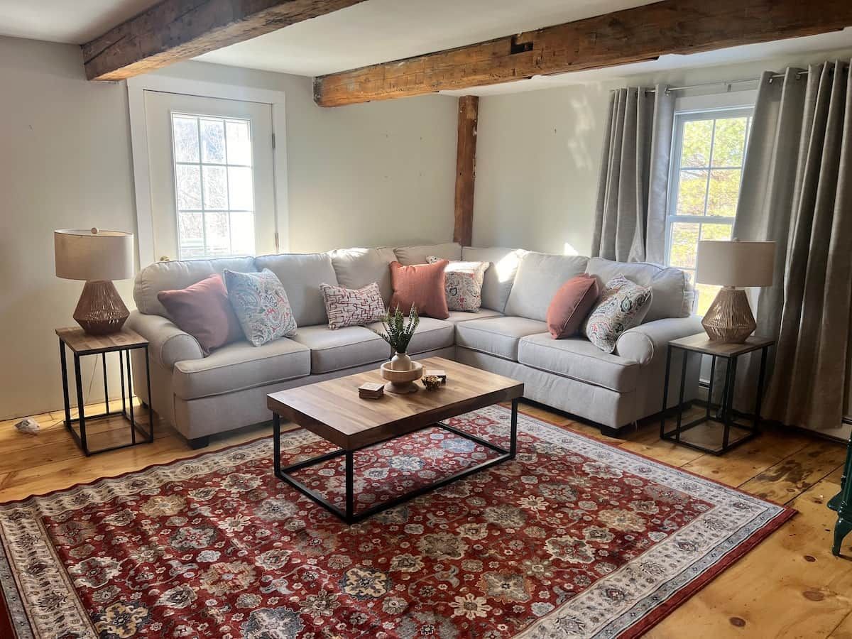 A living room with a sectional sofa, a coffee table, and a patterned rug.