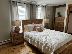 Ein Schlafzimmer mit einem hölzernen Bett, zwei Nachttischen, einer Lampe und einer Kommode.