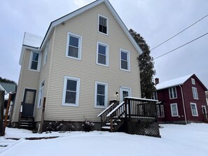 A two-story house with a front porch and a staircase leading to the entrance.