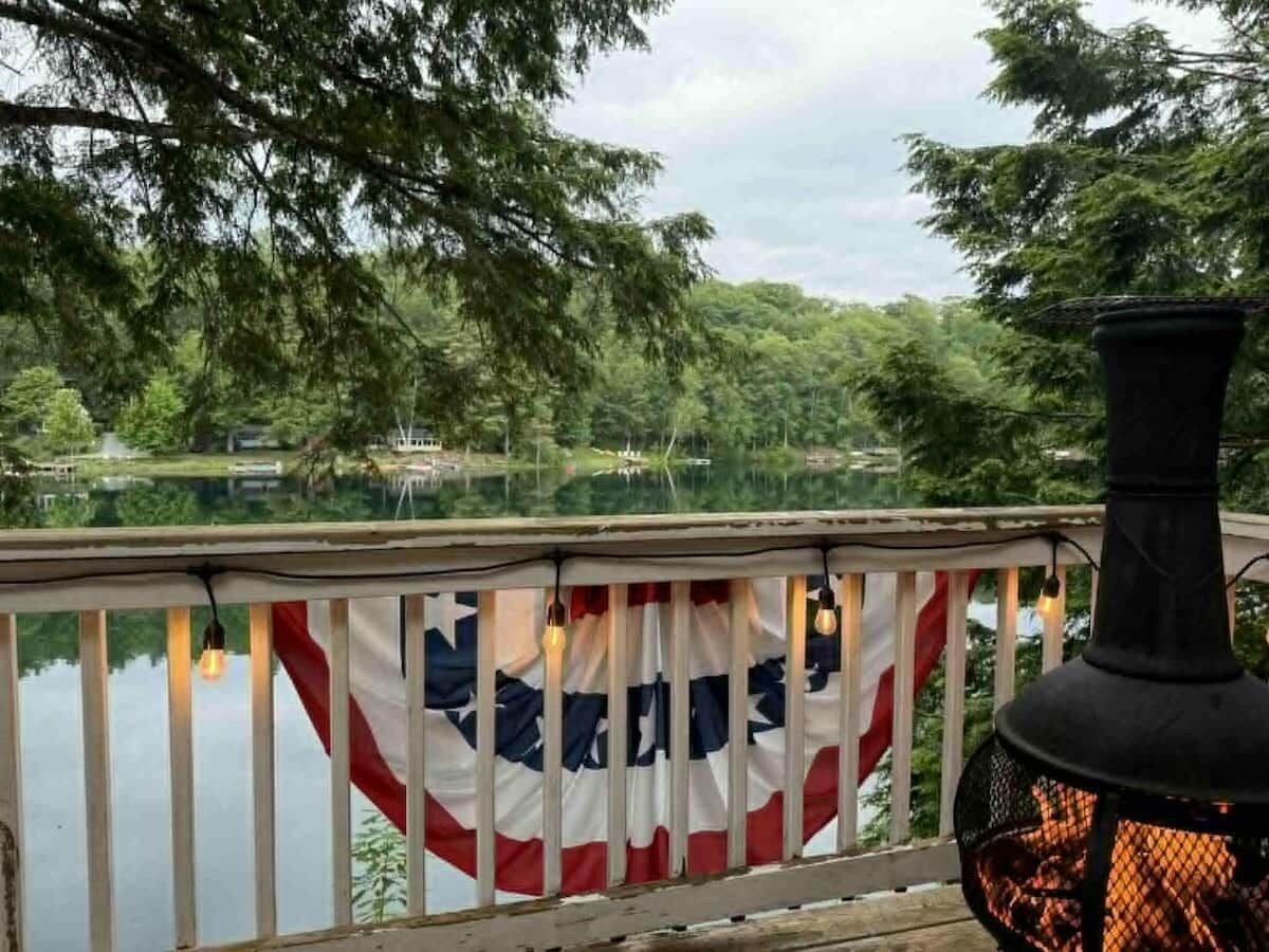 A deck with a flag, a fire feature, and a view of a lake.