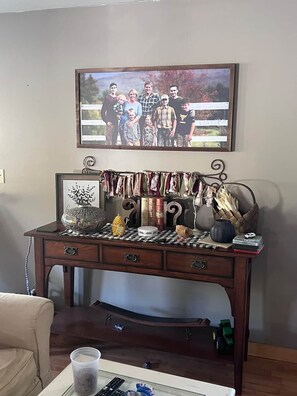 A wooden desk with a family photo, a decorative vase, and various items on top. - Reflections on the Lake (Hampton)