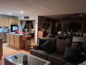 A living room with a sofa, a coffee table, and a kitchen area with cabinets and a countertop. - Reflections on the Lake (Hampton)