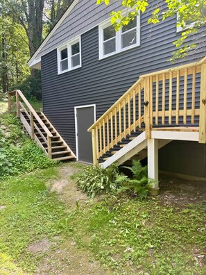A two-story house with a wooden staircase leading to a front door. - Couple’s Retreat near Killington with Hot Tub (Mendon)