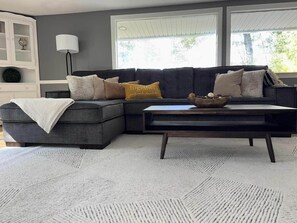 A living room with a sectional sofa, a coffee table, and a large rug. - Couple’s Retreat near Killington with Hot Tub (Mendon)