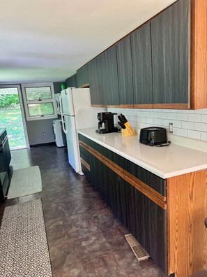 A modern kitchen with dark wood cabinets, a white countertop, and a built-in oven. - Couple’s Retreat near Killington with Hot Tub (Mendon)