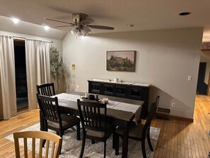 A dining area with a table, chairs, a ceiling fan, a cabinet, and a painting on the wall. - Cozy Killington Mountain Retreat with Hot Tub (Killington)