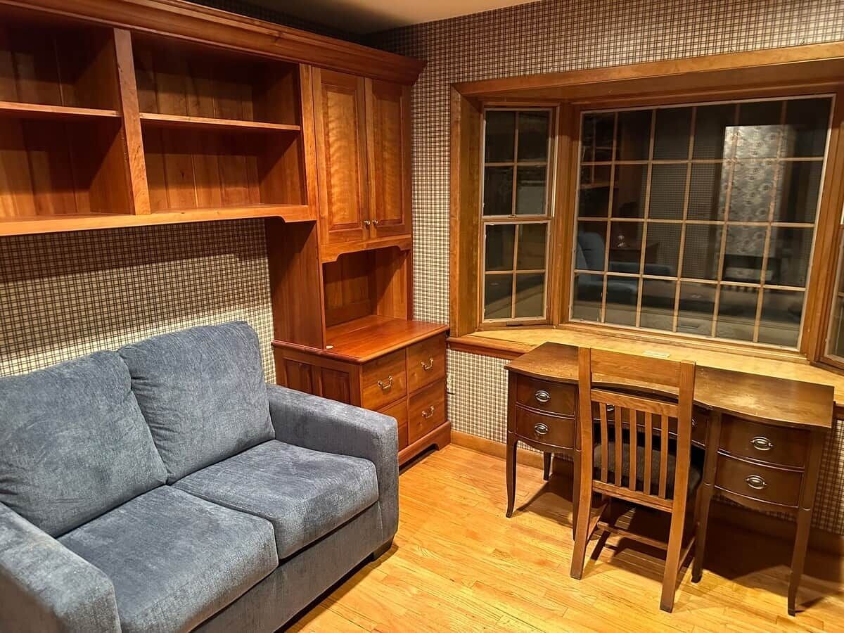 A room with a wooden desk, a blue sofa, and a window with a view.