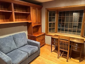 A room with a wooden desk, a blue sofa, and a window with a view. - Cozy Killington Mountain Retreat with Hot Tub (Killington)
