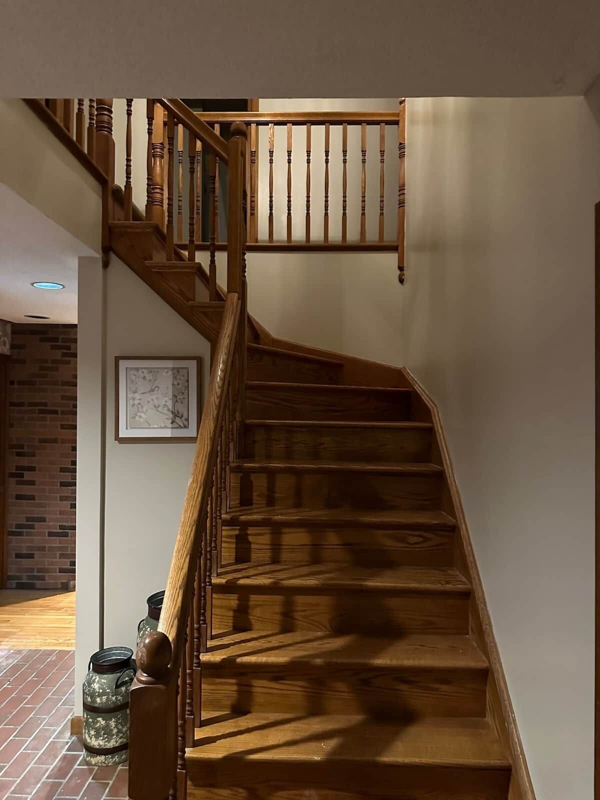Un escalier en bois avec une rampe et un tableau accroché au mur.